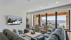 Ein modernes Wohnzimmer mit großem Fenster, Flachbildfernseher und gemütlicher Sitzecke.