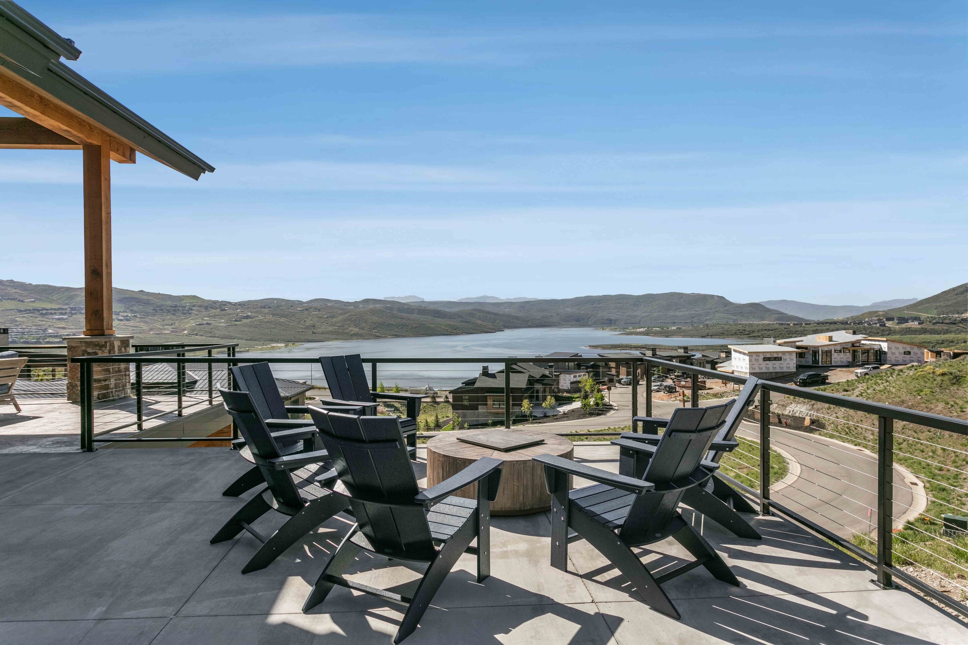 Une terrasse avec des sièges extérieurs et une vue sur un lac et des collines.