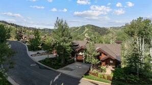 A residential area with houses, a curved driveway, and a hilly landscape in the background.