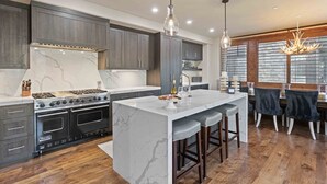 A modern kitchen with a large island, dark wood cabinets, and a built-in oven.