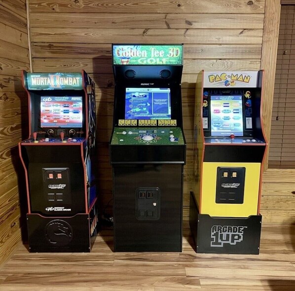 Trois bornes d’arcade : Mortal Kombat, Golden Tee 3D Golf et Pac-Man.