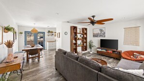 Ein modernes Wohnzimmer mit einer Couch, einem Esstisch und einem Fernseher.