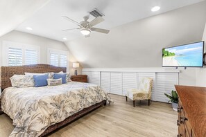 Quarto com cama, ventilador de teto, televisão, cadeira e cômoda.