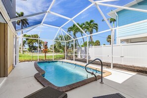 Piscina ao ar livre coberta com vista para palmeiras e um quintal cercado.