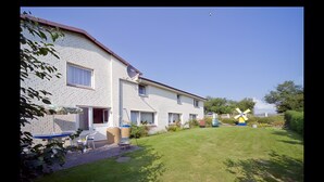 A two-story residential building with a brick facade, a satellite dish, and a windmill in the yard. - Apartment 'Fewo Nordstern Familie Sauerwald' with Shared Garden and Wi-Fi (Pellworm)