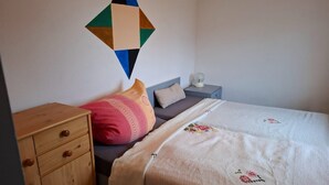 A bedroom with a bed, a nightstand, a dresser, and a wall decoration. - Apartment 'Fewo Nordstern Familie Sauerwald' with Shared Garden and Wi-Fi (Pellworm)
