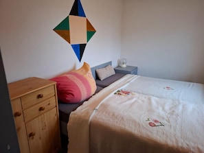 A bedroom with a bed, a nightstand, a dresser, and a wall decoration.