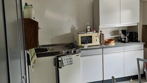 Eine kleine Küche mit Kühlschrank, Mikrowelle, Kaffeemaschine und Spüle.
