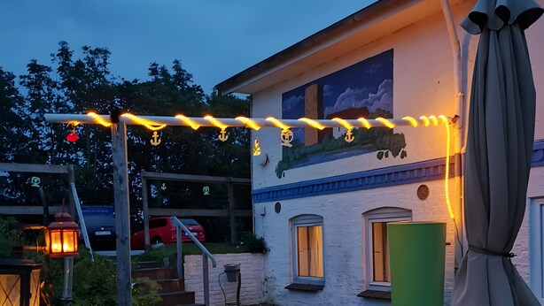 Eine Außenpatio mit Esstisch, einer Bank und einem Wandgemälde an der Gebäudefassade.