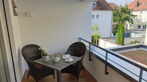 A balcony with wicker chairs, a table, and a potted plant. - Top equipped apartment in a central location in Freilassing (Freilassing)