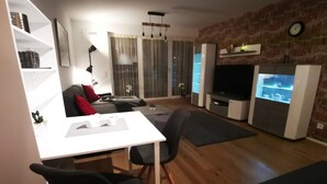 A modern living room with a white table, black chairs, a grey sofa, and a TV stand. - Top equipped apartment in a central location in Freilassing (Freilassing)