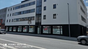A modern building with a white facade, multiple windows, and a sign indicating a parking area. - Top equipped apartment in a central location in Freilassing (Freilassing)