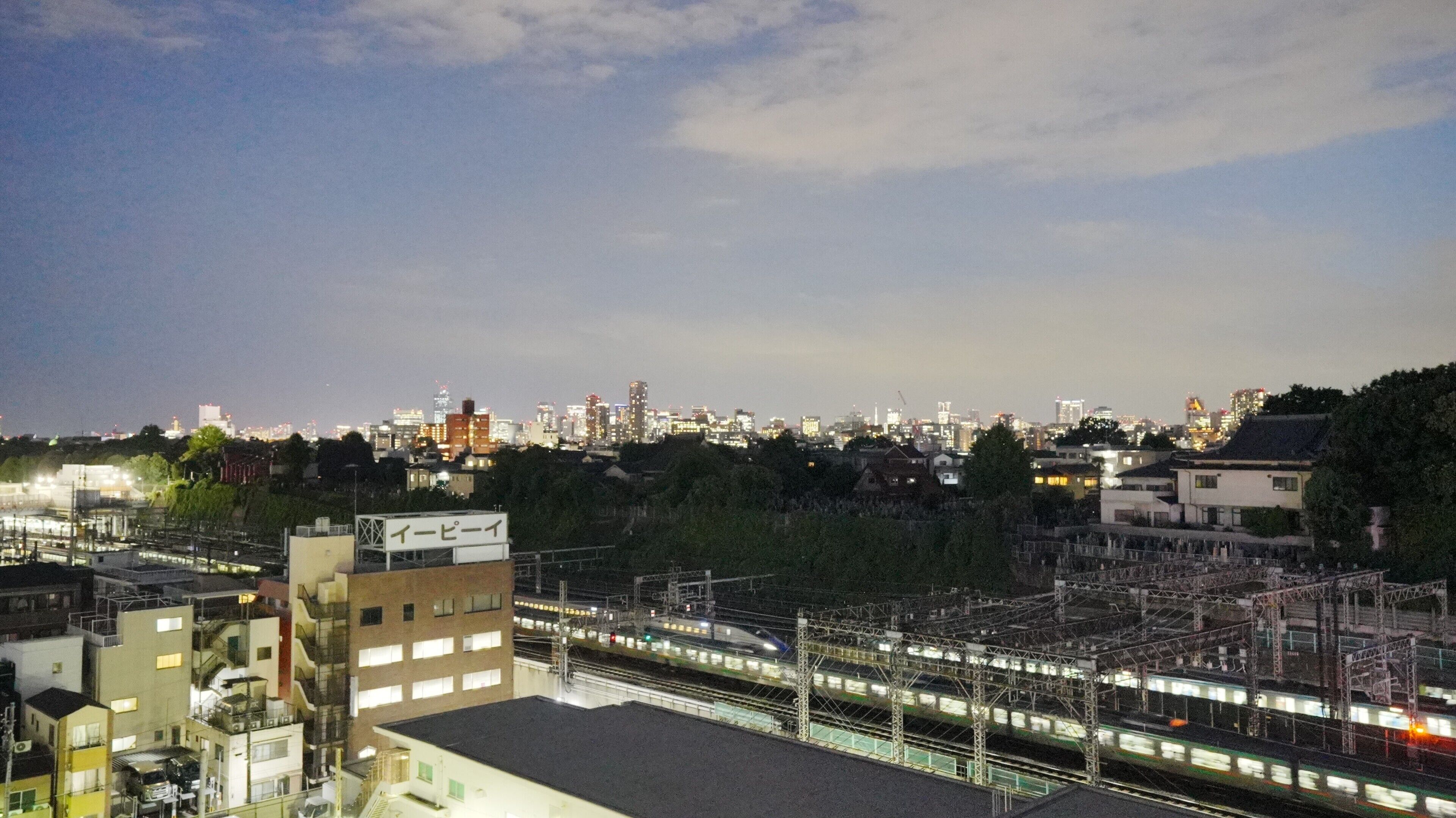 A nighttime cityscape with a train station and urban buildings.