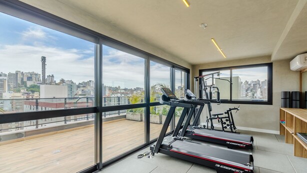 A modern apartment with large windows, a treadmill, and a home gym setup. - Apartment in Condominium With Gym in PoA - Ips0701 (Porto Alegre)