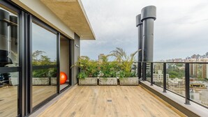 A balcony with a view of a cityscape, large windows, and a concrete planter with plants. - Apartment in Condominium With Gym in PoA - Ips0701 (Porto Alegre)