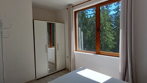 Een kamer met een garderobe, een kapstok en een raam met uitzicht op bomen.