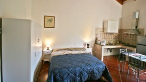 A bedroom with a bed, a nightstand, a bedside lamp, a small table, and a chair. - The Scola of Pirazzolu Retreat (Olbia)