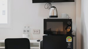 A compact kitchenette with a microwave, kettle, and a flat-screen TV mounted above it. - Kavana Kata Residence (Karon)