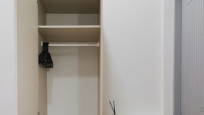 A room with a wardrobe, a small table with a vase, and a door. - Kavana Kata Residence (Karon)