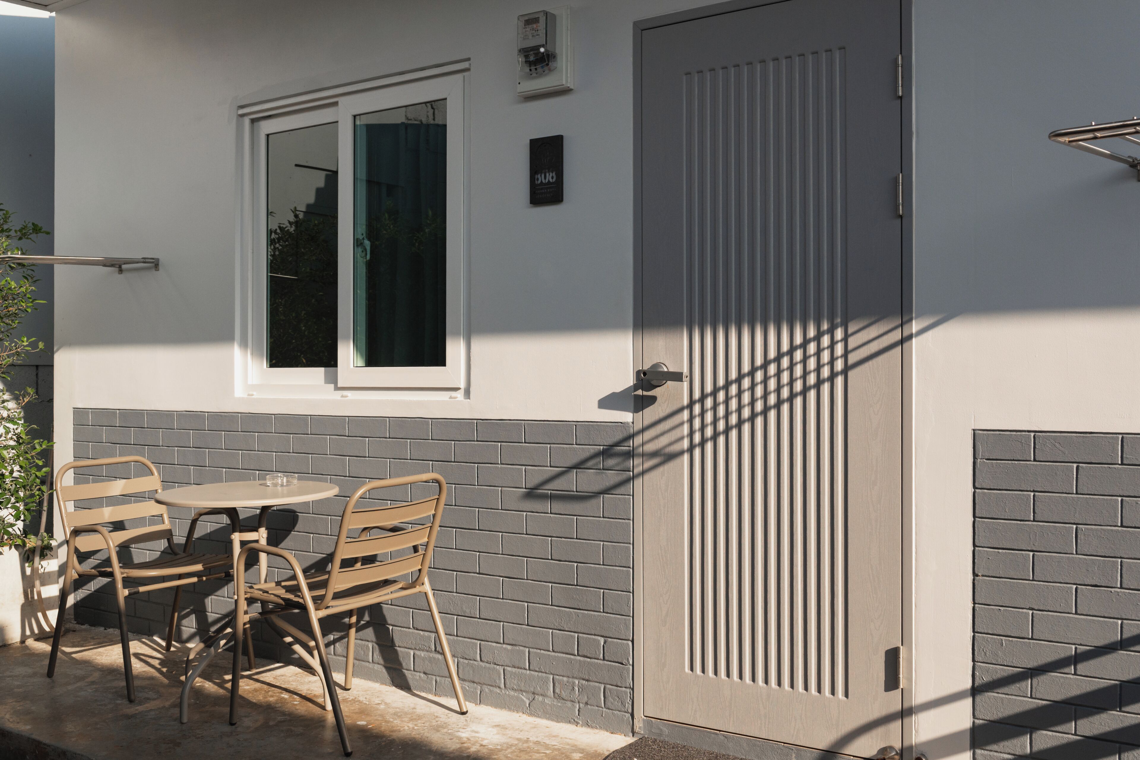 Un patio con mesa y sillas, una puerta con ventanal y un aplique de pared.