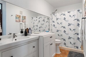 Un bagno con un lavandino bianco, un water e una tenda da doccia con un motivo di uccelli.