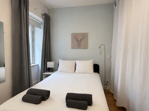 Ein ordentlich bezogenes Bett mit weißen Leinentüchern, zwei Kissen und zwei zusammengerollten Handtüchern.