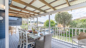 A covered outdoor dining area with a table set for two, surrounded by wicker chairs. - The Salty Sailor, 7 Market St - Wi-Fi, Water views, Air Con, Boat Parking (Fingal Bay)