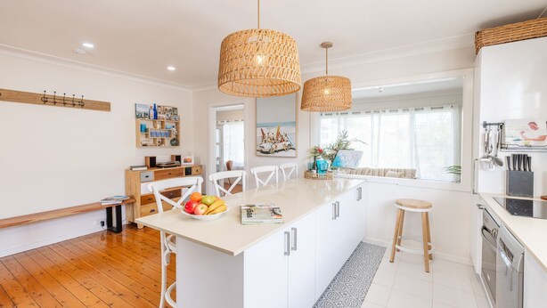 A modern kitchen with a central island, wooden flooring, and pendant lighting. - The Salty Sailor, 7 Market St - Wi-Fi, Water views, Air Con, Boat Parking (Fingal Bay)