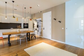 Une cuisine moderne avec un plancher en bois, une table à manger et des luminaires suspendus.