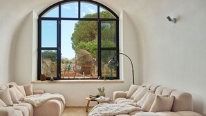 A room with a large arched window, two beige sofas, a small wooden table, and a floor lamp.