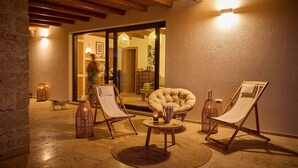 A cozy outdoor seating area with two lounge chairs, a round table, and a wicker lamp.