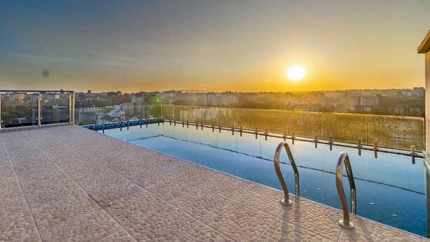 Une piscine sur le toit offrant une vue dégagée sur les gratte-ciel de la ville au coucher du soleil.