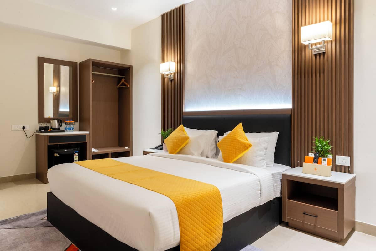 Une chambre d’hôtel moderne avec un grand lit, une armoire, une table de chevet avec une lampe et une petite plante sur la table de chevet.