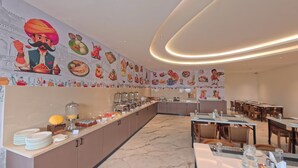 Un espace buffet proposant une variété de plats et orné d’une fresque représentant des aliments et des personnes.