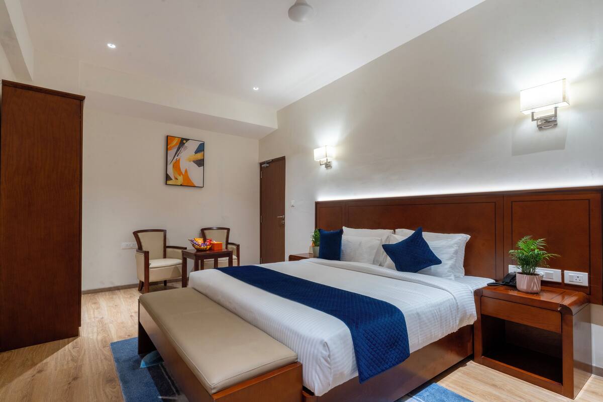 Une chambre d’hôtel moderne avec un grand lit, une banquette, un bureau et une chaise.