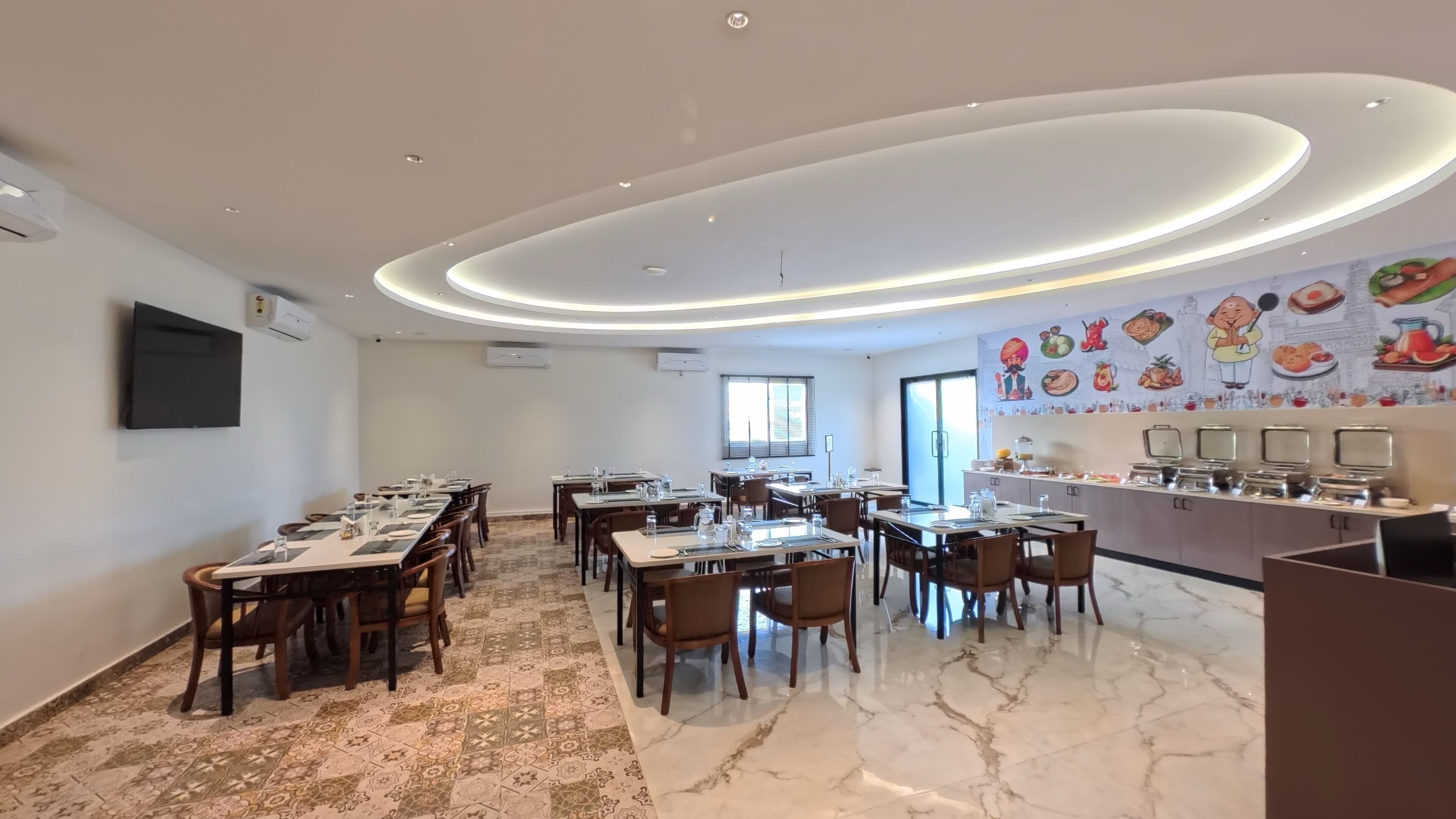 A modern dining area with multiple tables and chairs, a kitchen counter with appliances, and a mural depicting food items on the wall.