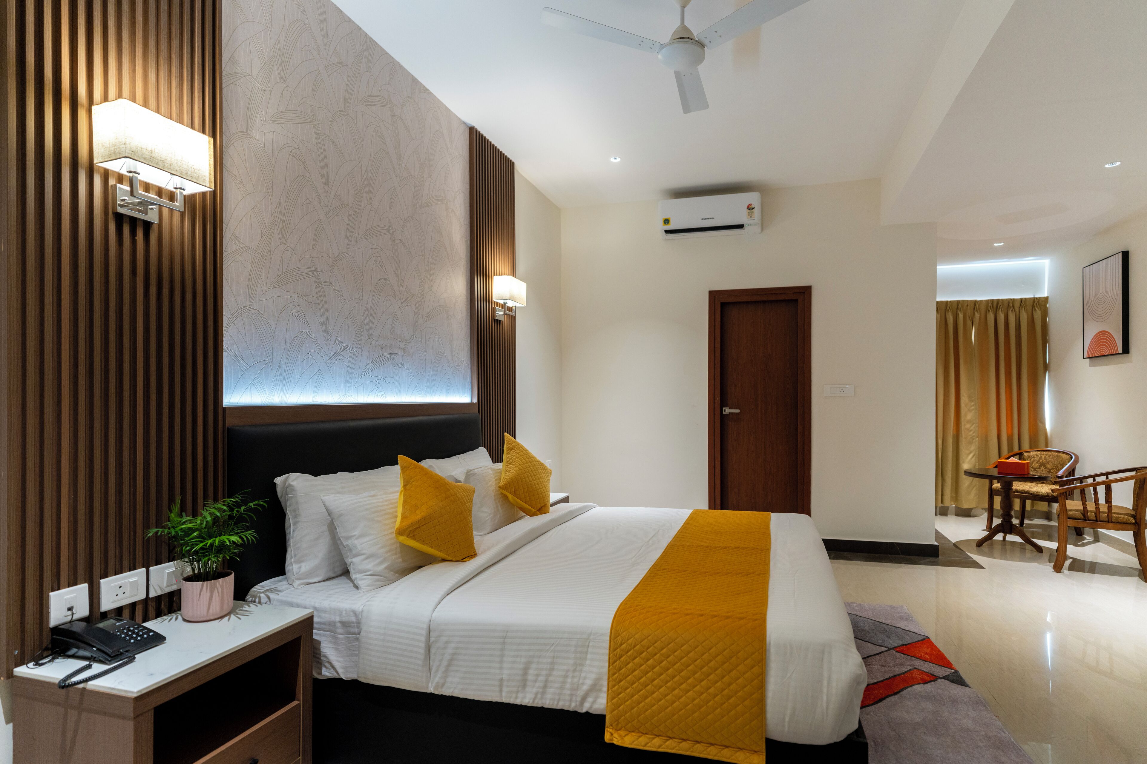A modern hotel room with a bed, bedside table, lamp, and a small desk with a telephone.