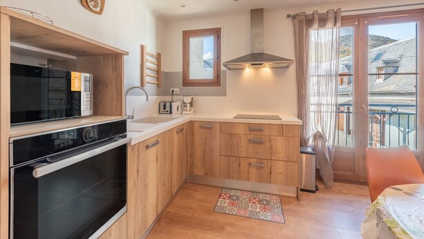 Une cuisine moderne avec des meubles en bois, un four encastré et une fenêtre avec des rideaux.