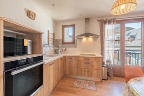 Una cocina moderna con armarios de madera, horno empotrado y ventana con cortinas.