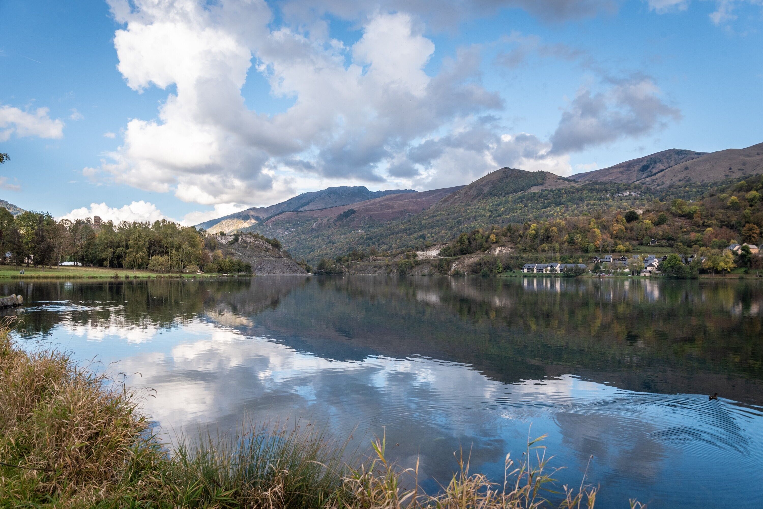 Un lago tranquilo con montañas al fondo y un cielo despejado.