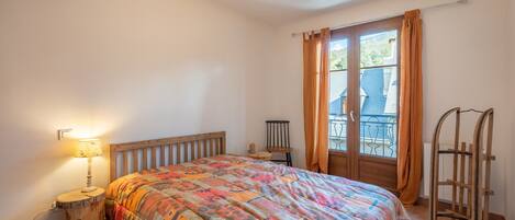 Una camera da letto con un letto in legno, un comodino con una lampada, una finestra con tende e una scala in legno.