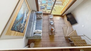 Quarto moderno estilo loft, com uma janela grande, sofá, mesa pequena e um quadro na parede.