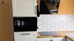 A kitchen with white cabinets, a microwave, a gas stove, and a hexagonal tile backsplash. - Family Housing (2 Adults + 1 Child) - Center City (MIREPOIX)
