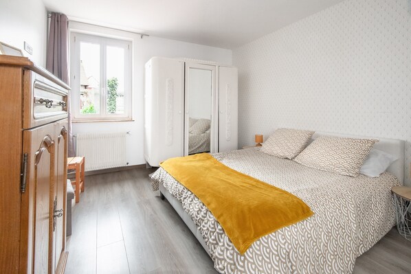 A bedroom with a bed, a wardrobe, a window, and a radiator.