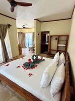 A hotel room with a large bed, a wooden wardrobe, and a ceiling fan.