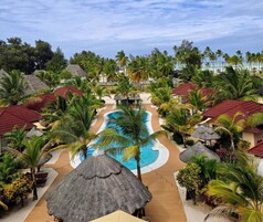 A resort with a central swimming pool, thatched-roof structures, and palm trees.