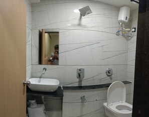 A bathroom with a white sink, toilet, and a mirror. - Hotel Earth Orbit (Gandhinagar)