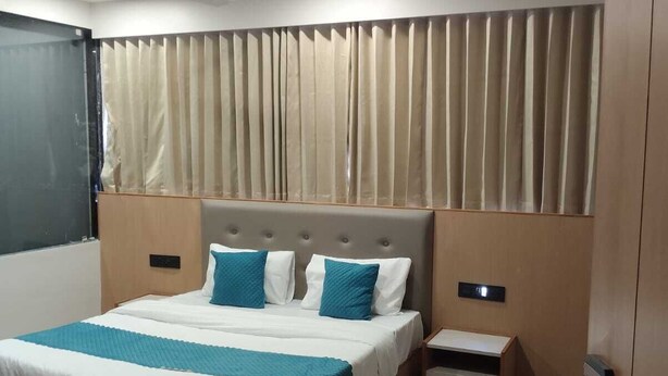Una habitación de hotel moderna con una cama grande, mesitas de noche, un escritorio y un televisor.