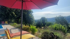 A poolside area with a red umbrella, lounge chairs, and a view of the surrounding landscape. - L'Annexe de la Bastide - Stone house with swimming pool (Ribes)