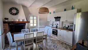 A modern kitchen with white cabinets, a dining table with chairs, a hanging light fixture, and patterned floor tiles. - L'Annexe de la Bastide - Stone house with swimming pool (Ribes)